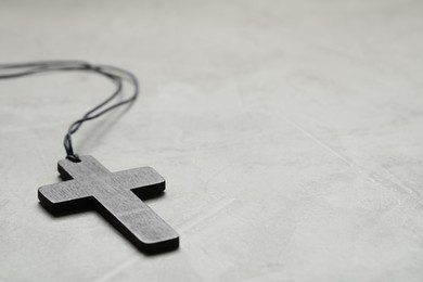Photo of Wooden Christian cross on light grey table, closeup. Space for text