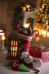 Photo of Stocking, sweets, gift box and lantern on table. Saint Nicholas Day tradition