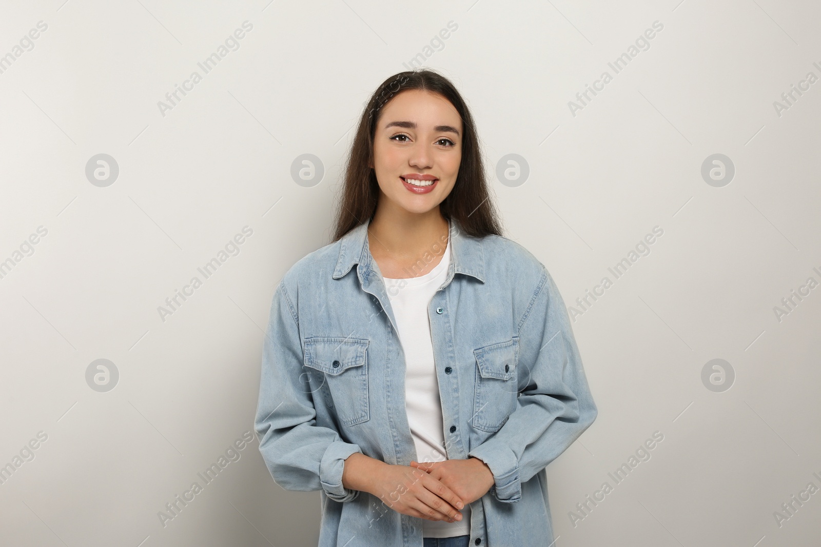 Photo of Portrait of happy young woman in jeans jacket on white background