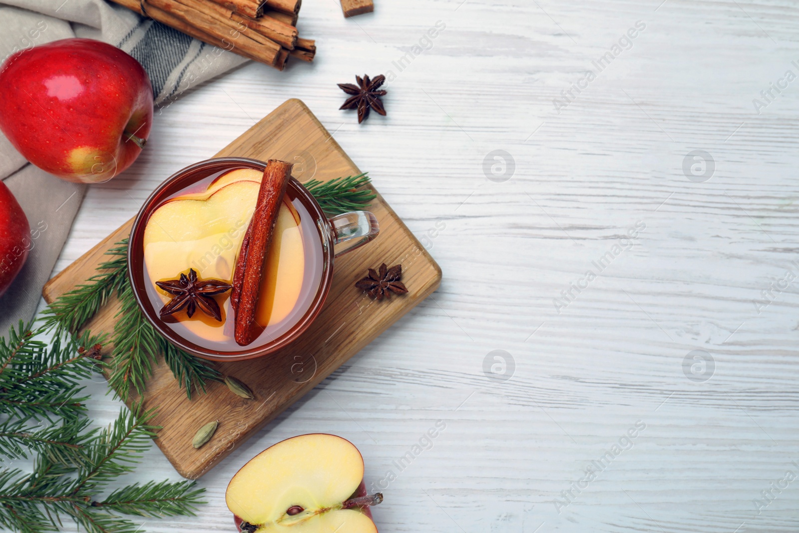 Photo of Aromatic hot mulled cider on white wooden table, flat lay. Space for text