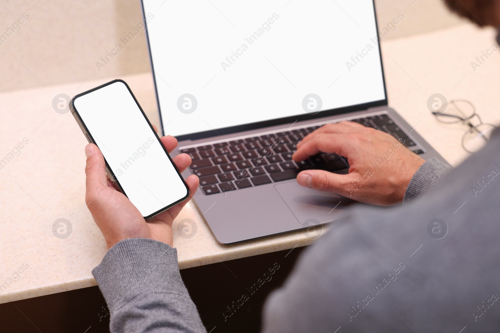 Photo of Man using smartphone and laptop at table in cafe, closeup