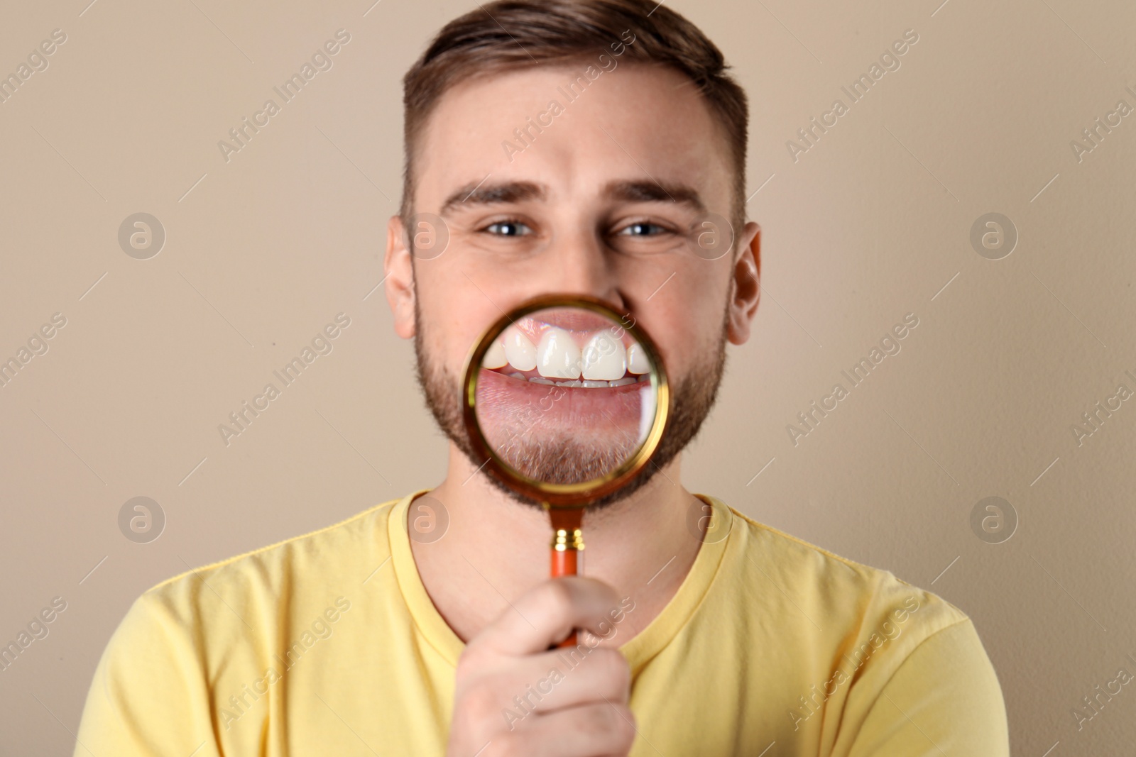 Photo of Young man with healthy teeth and magnifier on color background