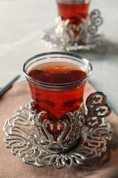 Photo of Glasses of traditional Turkish tea in vintage holders on table, closeup