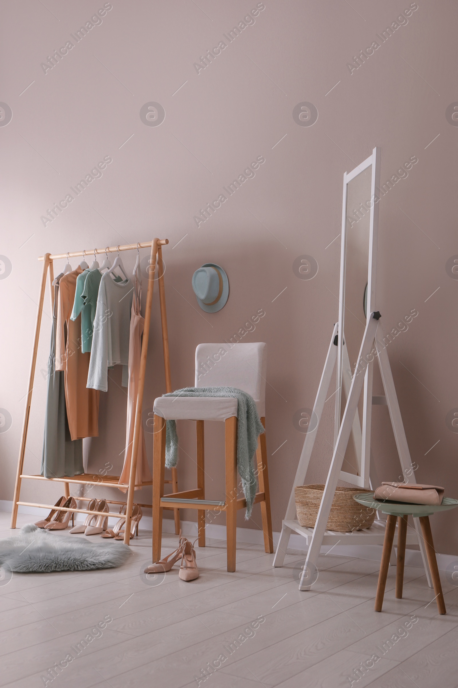 Photo of Modern dressing room interior with clothing rack, stool and mirror