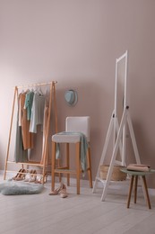 Photo of Modern dressing room interior with clothing rack, stool and mirror