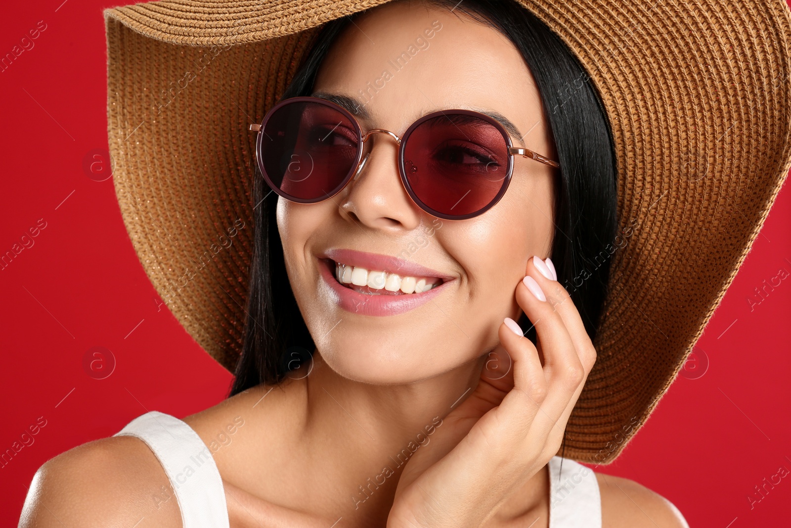 Photo of Beautiful woman wearing sunglasses on red background, closeup