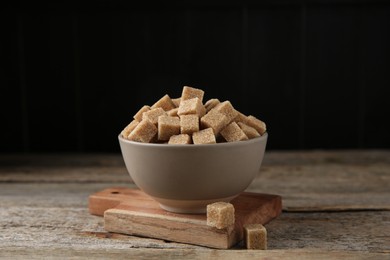 Photo of Bowl with brown sugar cubes on wooden table