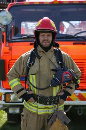 Portrait of firefighter in uniform near fire truck outdoors