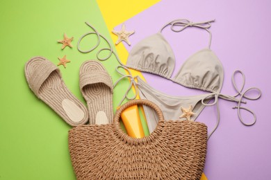 Stylish bag with beach accessories on color background, flat lay