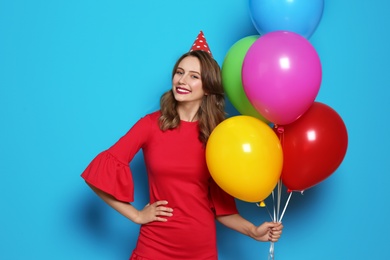 Young woman with bright balloons on color background. Birthday celebration