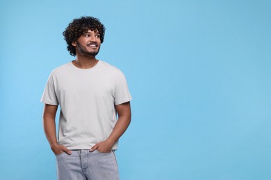 Photo of Handsome smiling man on light blue background, space for text