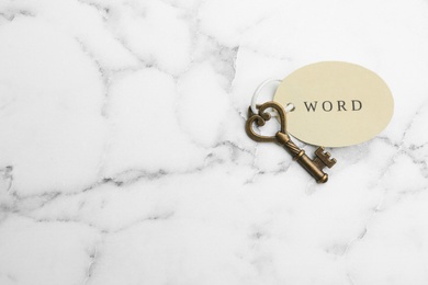 Photo of Vintage key with tag on white marble table, top view and space for text. Keyword concept