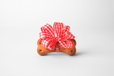 Photo of Bone shaped dog cookie with bow on white background