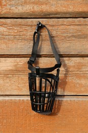 Black dog muzzle hanging near wooden fence