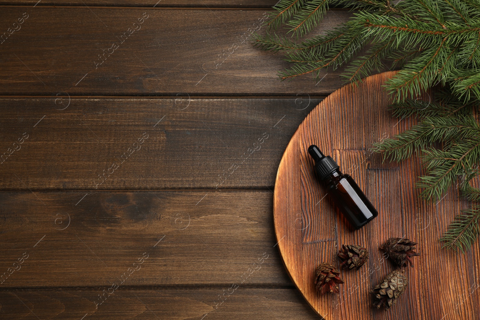 Photo of Pine essential oil, cones and branches on wooden table, flat lay. Space for text