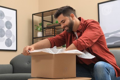 Photo of Man unpacking parcel at home. Online shopping