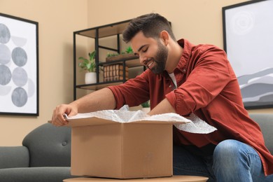 Man unpacking parcel at home. Online shopping