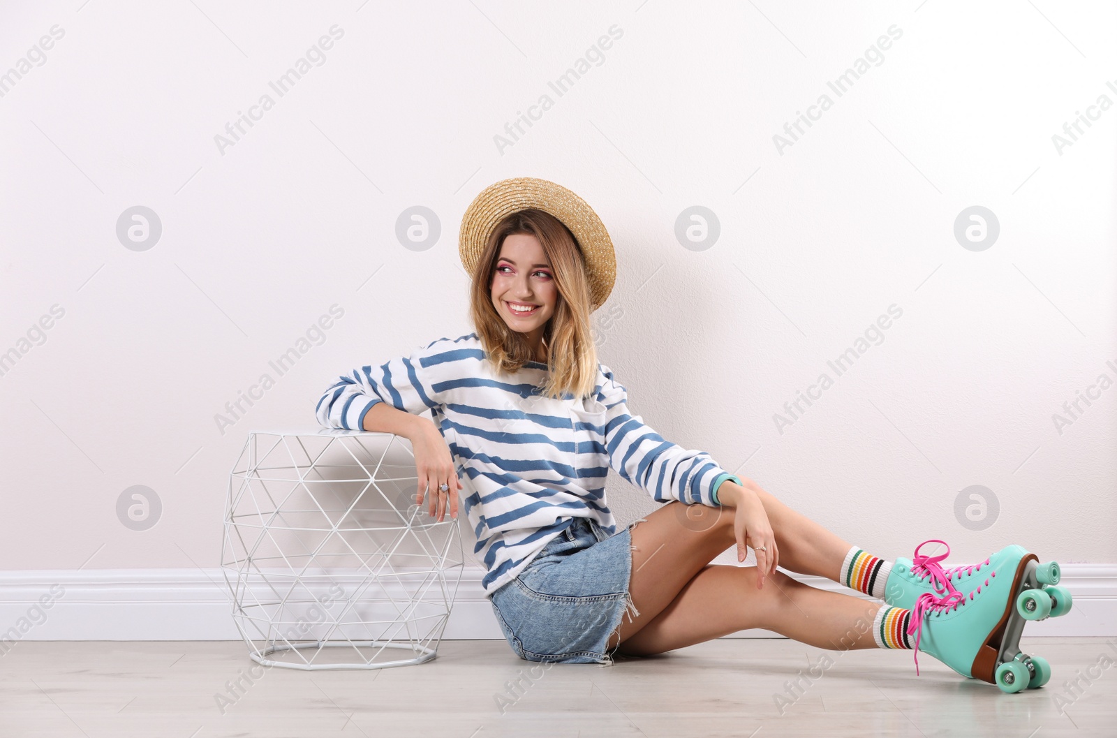 Photo of Young woman with retro roller skates near white wall
