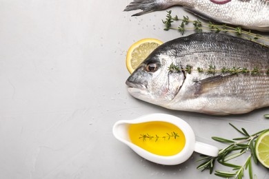 Flat lay composition with fresh raw dorado fish and ingredients on light grey table, space for text