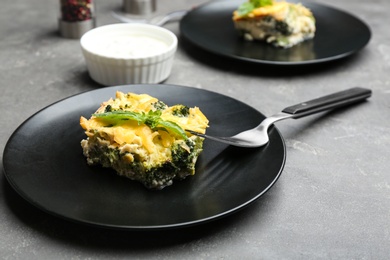 Photo of Piece of tasty broccoli casserole on grey table