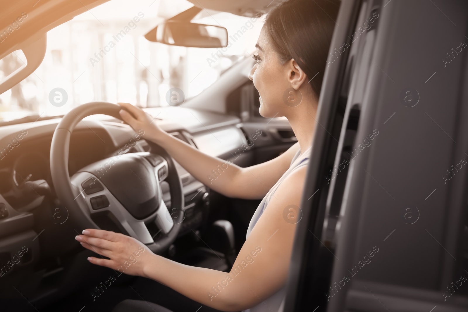 Photo of Young woman sitting in driver's seat of new car at salon