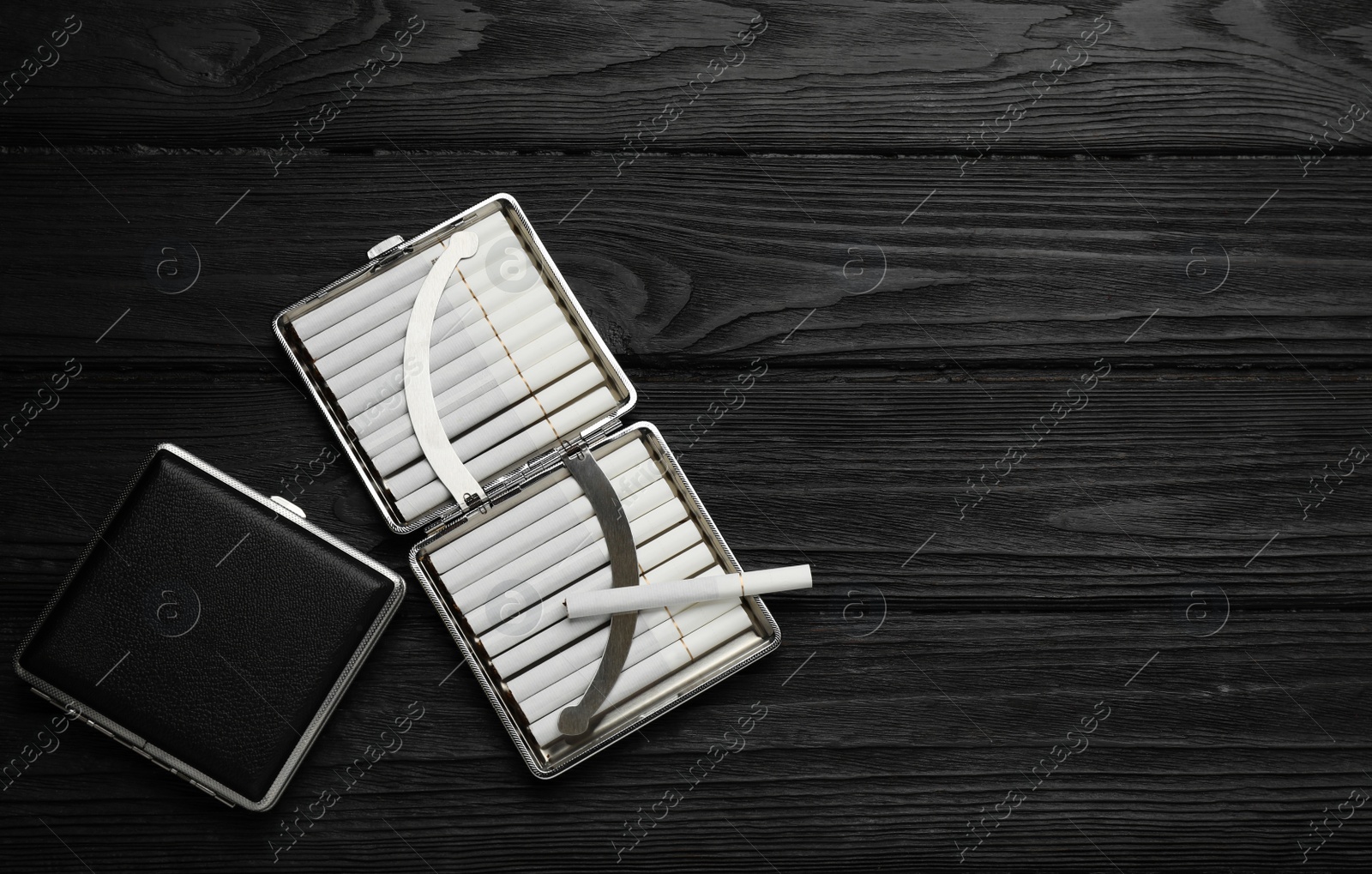 Photo of Stylish leather cigarette cases on black wooden table, flat lay. Space for text