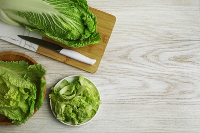 Photo of Whole and cut fresh ripe Chinese cabbage on white wooden table, flat lay. Space for text