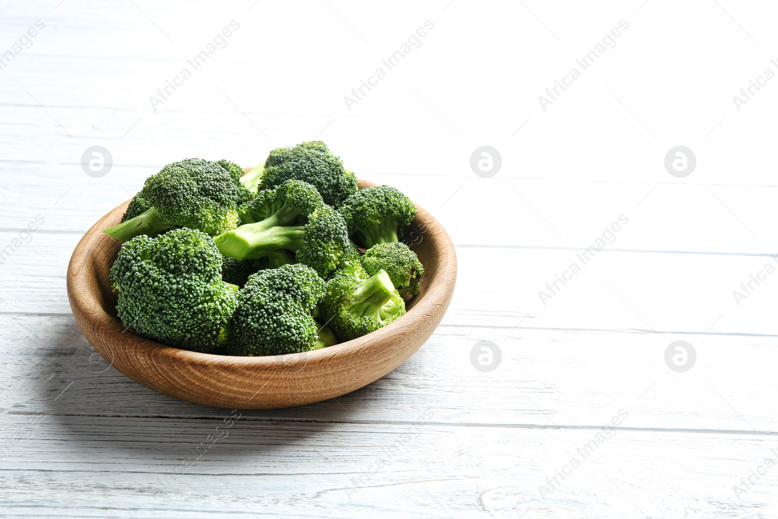 Photo of Plate of fresh green broccoli on white wooden table, space for text