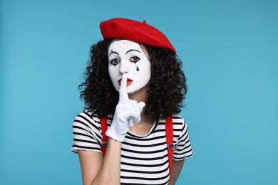 Photo of Funny mine with beret showing shush gesture on light blue background