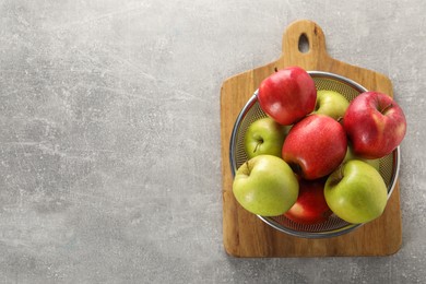 Photo of Fresh ripe apples in colander on light grey table, top view. Space for text