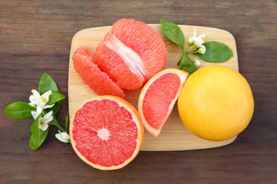 Photo of Fresh ripe grapefruits and green leaves on wooden table, top view