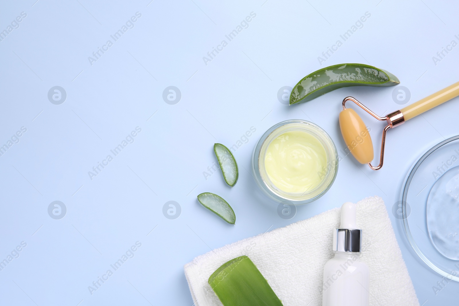 Photo of Flat lay composition with cosmetic products and cut aloe leaves on light blue background. Space for text