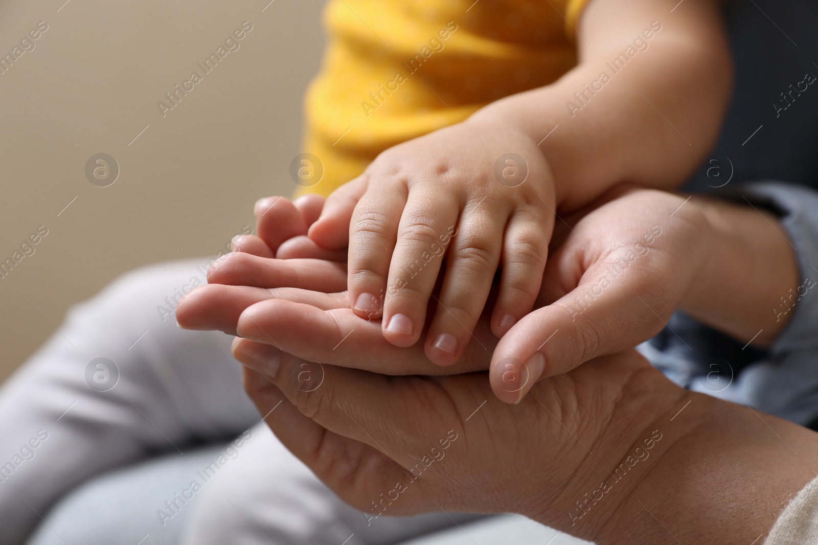 Photo of Family holding hands together on beige background, closeup