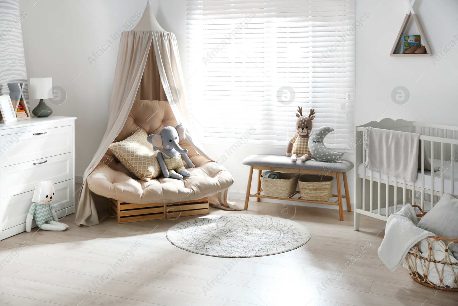 Photo of Beautiful baby room interior with comfortable armchair and bench near window