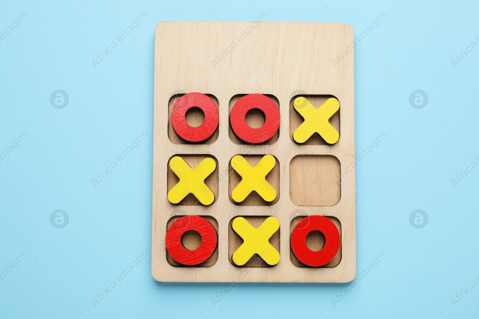 Photo of Tic tac toe set on light blue background, top view