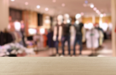 Image of Empty wooden table and blurred view of store with modern clothes