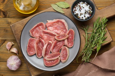 Photo of Raw beef tongue pieces and spices on wooden table, flat lay