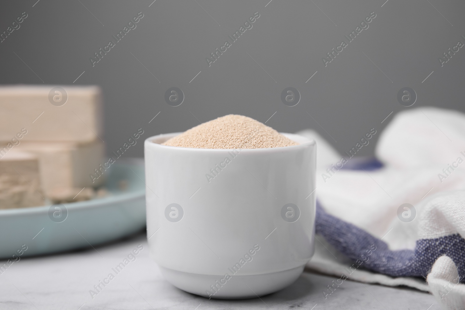 Photo of Granulated yeast in bowl on table, closeup