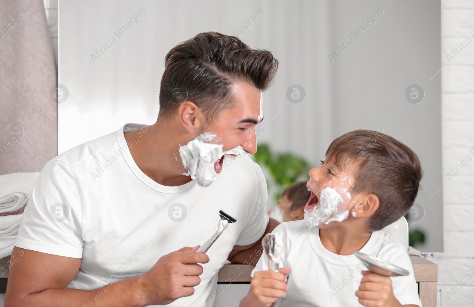 Photo of Father and son having fun while shaving in bathroom