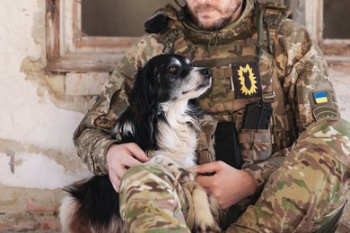 Photo of Ukrainian soldier with stray dog in abandoned building, closeup