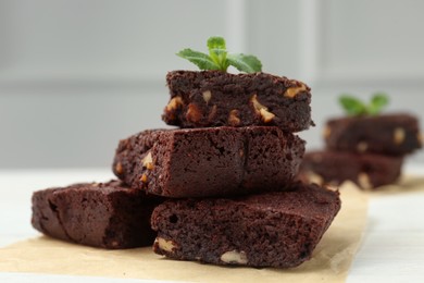 Delicious chocolate brownies with nuts and fresh mint on white table, closeup