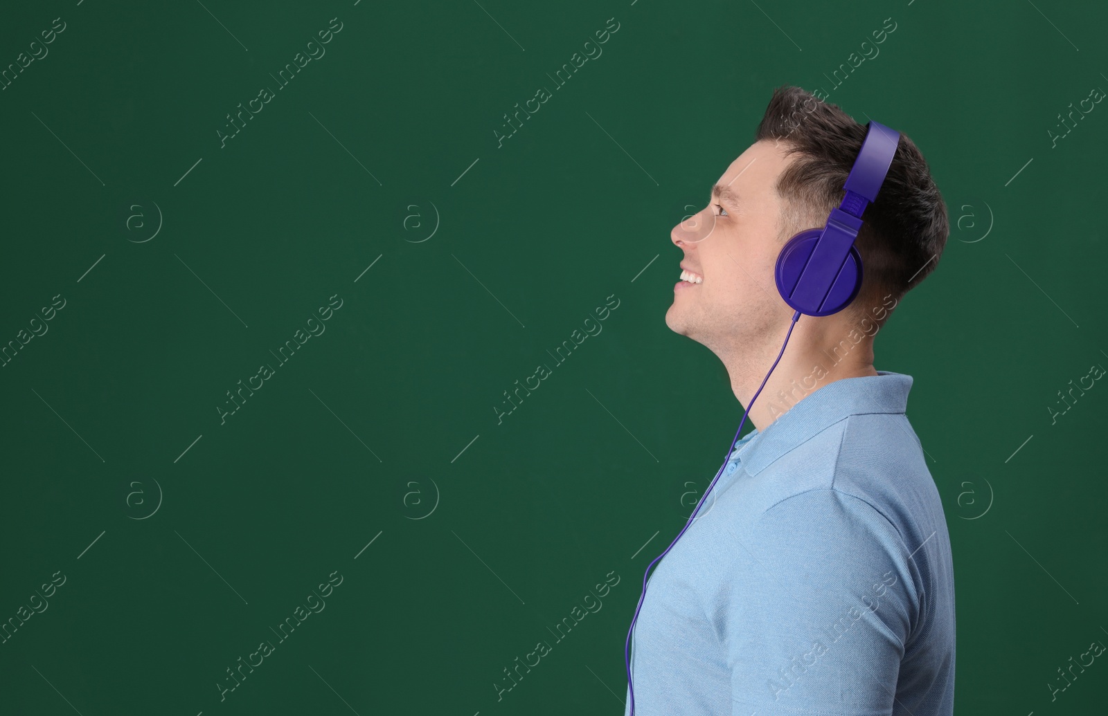 Photo of Man enjoying music in headphones on color background. Space for text