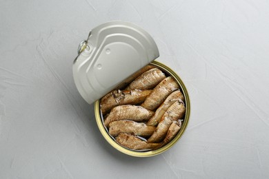 Photo of Open tin can of sprats on light grey table, top view