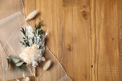 Photo of Stylish boutonniere and ribbon on wooden table, top view. Space for text