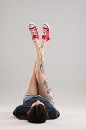 Woman with beautiful tattoos lying on grey background