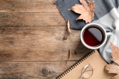Flat lay composition with cup of tea and autumn leaves on wooden table. Space for text