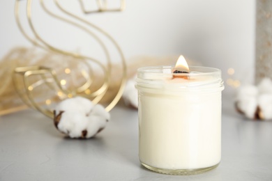 Burning candle with wooden wick on grey table