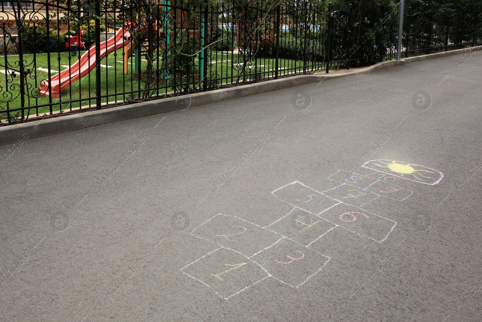 Photo of Hopscotch drawn with colorful chalk on asphalt outdoors