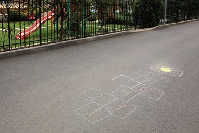 Photo of Hopscotch drawn with colorful chalk on asphalt outdoors