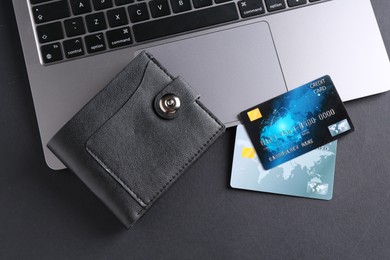 Photo of Credit cards, laptop and leather wallet on grey table, flat lay